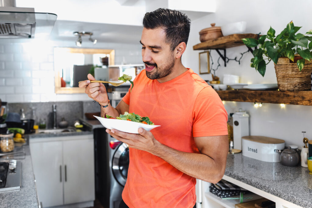 A man enjoying a nutritious bowl of salad in his kitchen