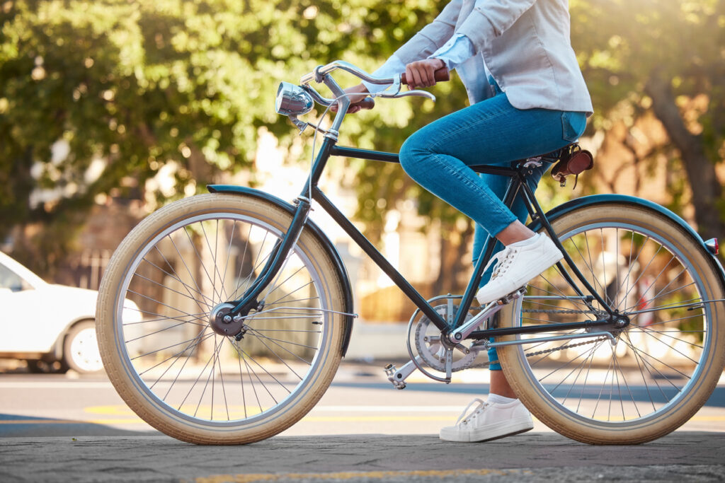 Someone bikes by on a sidewalk on a street bike with a city street