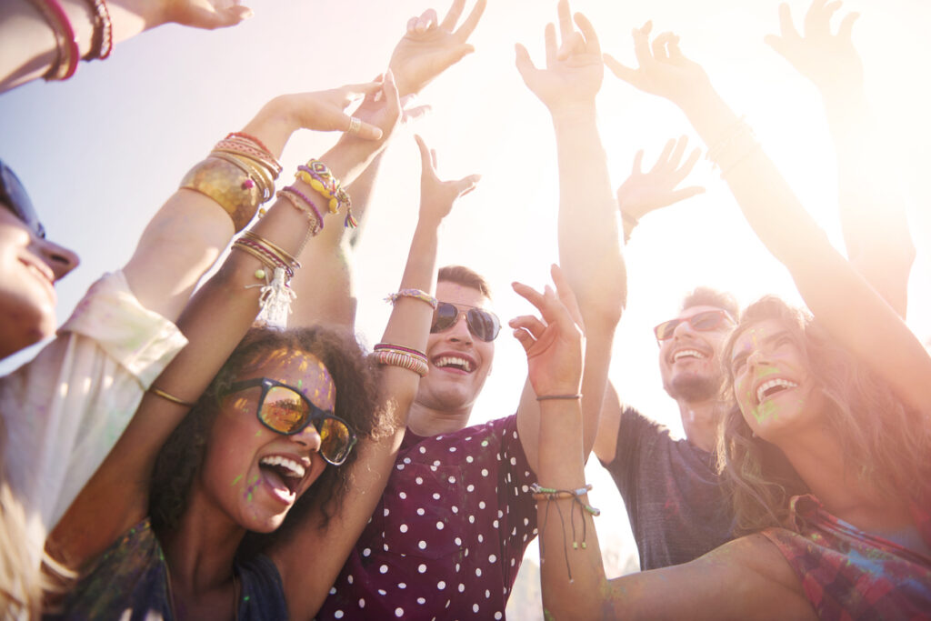 A group of diverse friends with their arms up in the air, enjoying a party